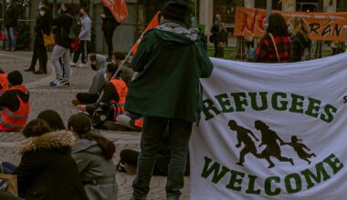 A person holding a banner saying 'Refugees Welcome'.