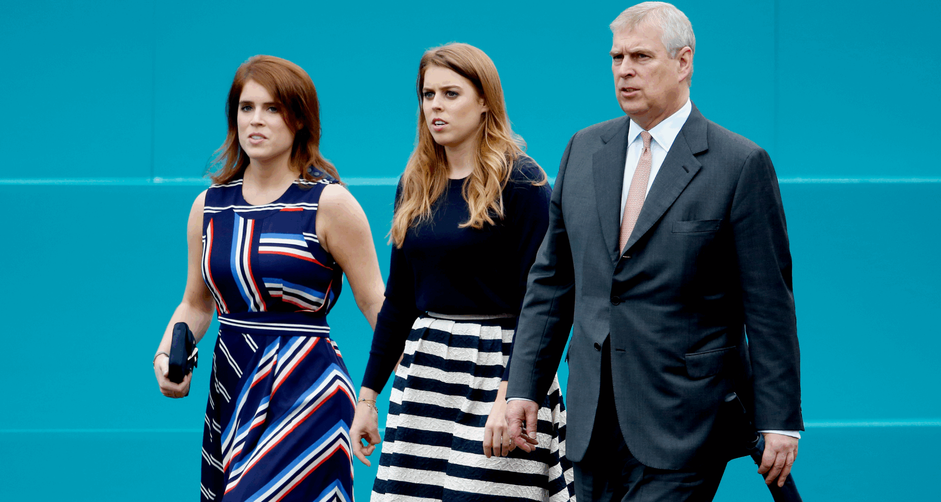 Princess Eugenie, Princess Beatrice and Prince Andrew walking in a row in front of a teal wall