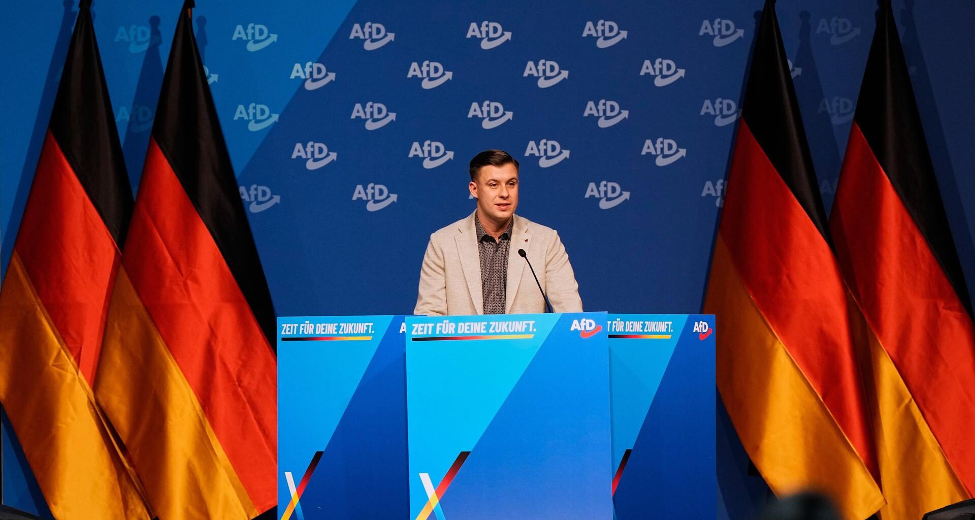 Der Chef der neuen AfD-Jugendorganisation Jean-Pascal Hohm beim Gründungsparteitag in Gießen - neben ihm stehen Deutschlandfahnen