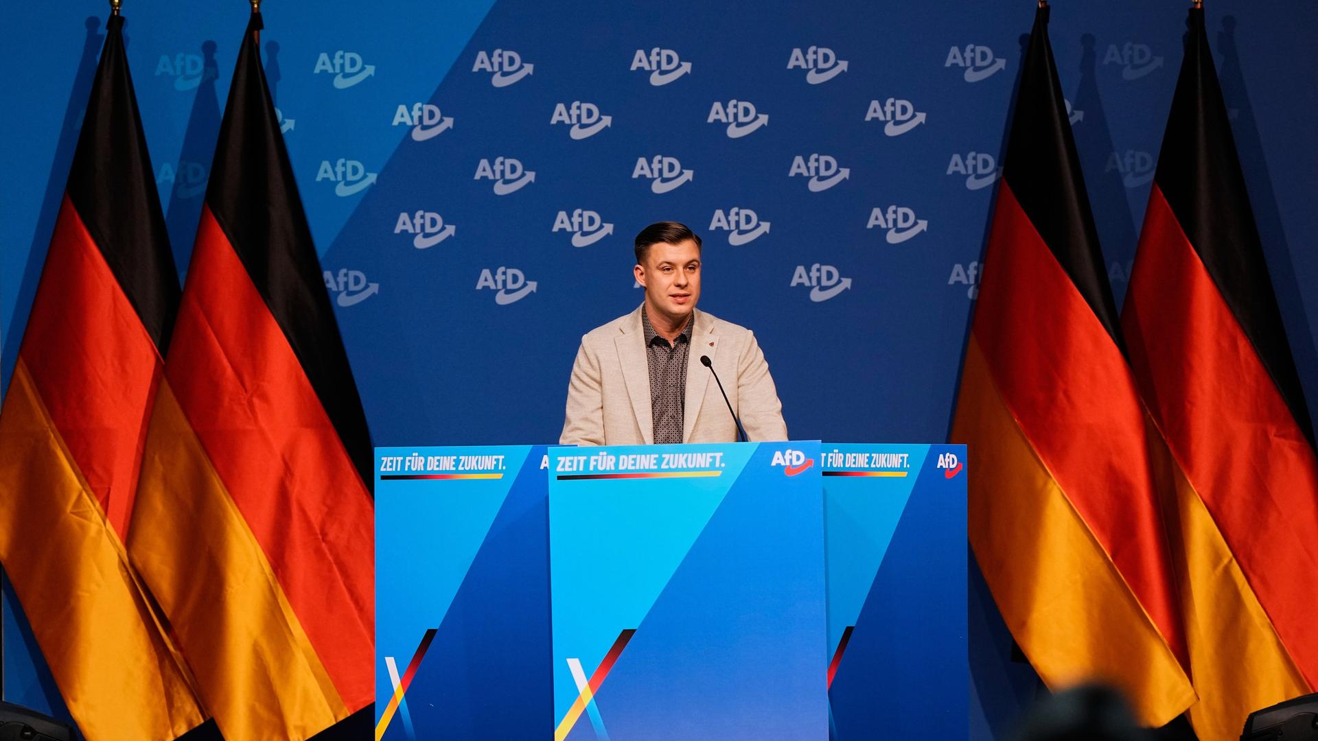 Der Chef der neuen AfD-Jugendorganisation Jean-Pascal Hohm beim Gründungsparteitag in Gießen - neben ihm stehen Deutschlandfahnen