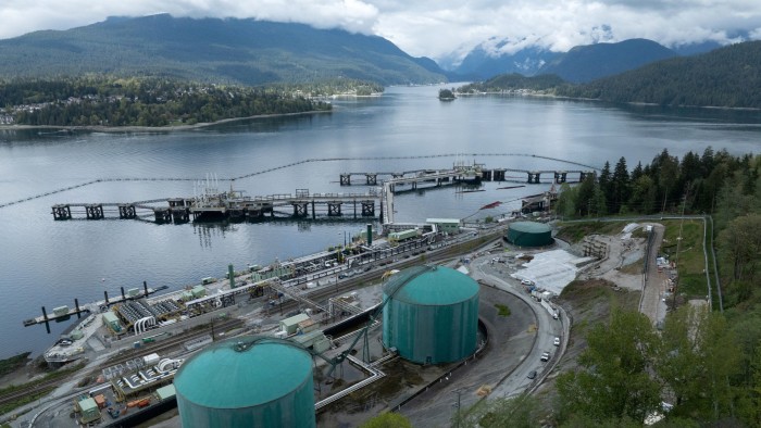 Aerial view of three oil-loading berths at Westridge Marine Terminal, with large green storage tanks and surrounding infrastructure.