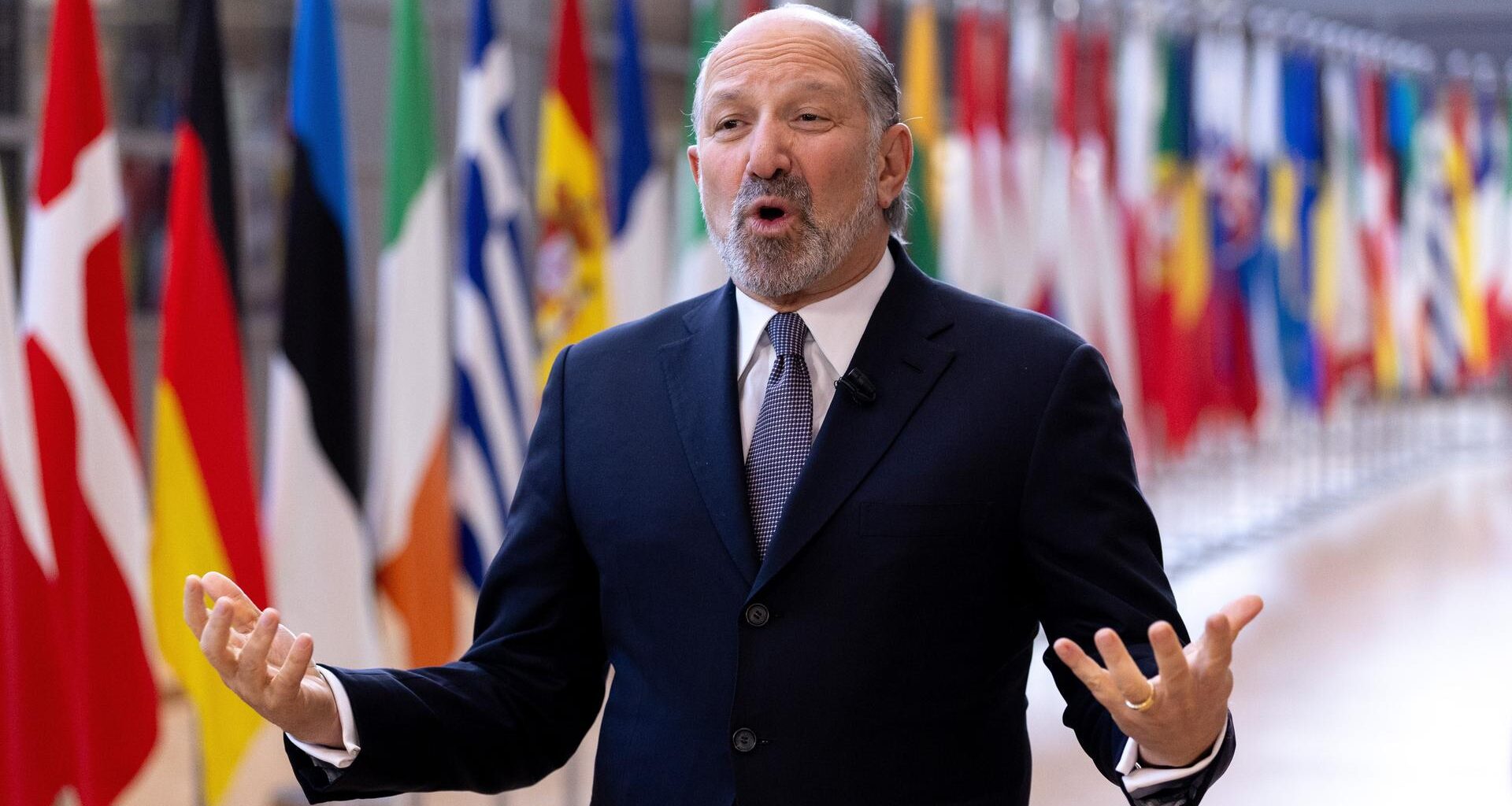 US-Handelsminister Howard Lutnick spricht und gestikuliert im Gebäude des Europäischen Rates in Brüssel. Hinter ihm sind die Flaggen der EU-Staaten.