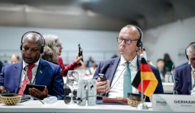 Bundeskanzler Friedrich Merz mit Kopfhörern an einem Konferenztisch.
