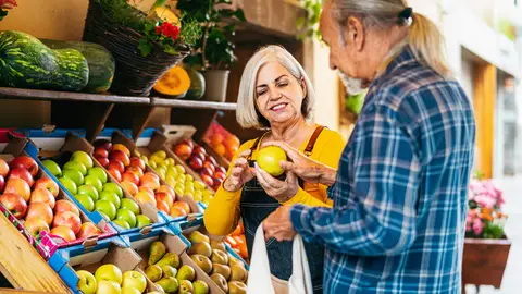 Mujer mayor atendiendo a un cliente en una frutería