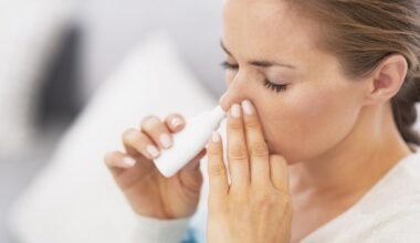 A woman demonstrates the use of nasal drops. (Adobe Stock Photo)
