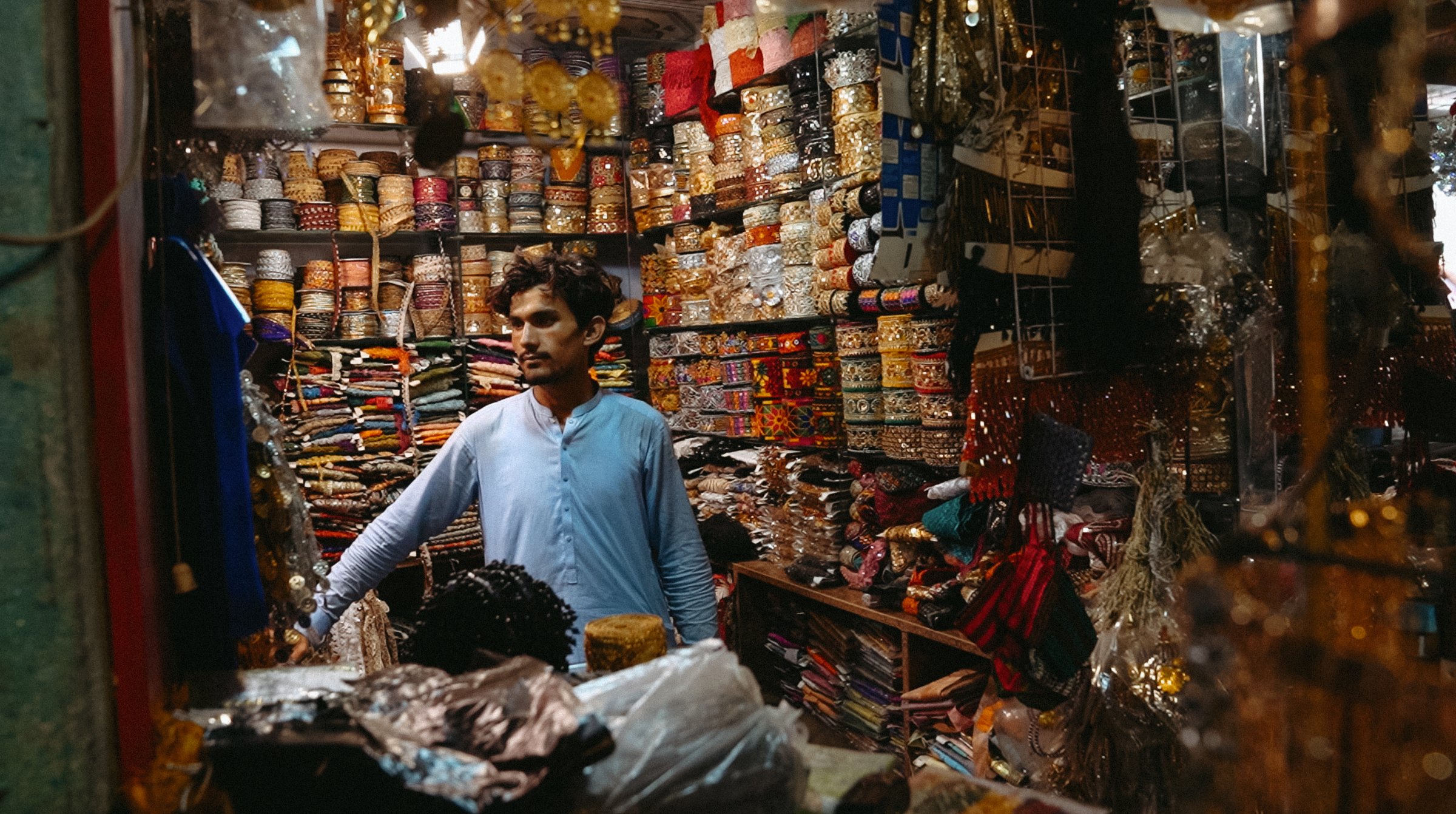 Un homme dans un magasin coloré rempli de tissus et d'ornements variés.