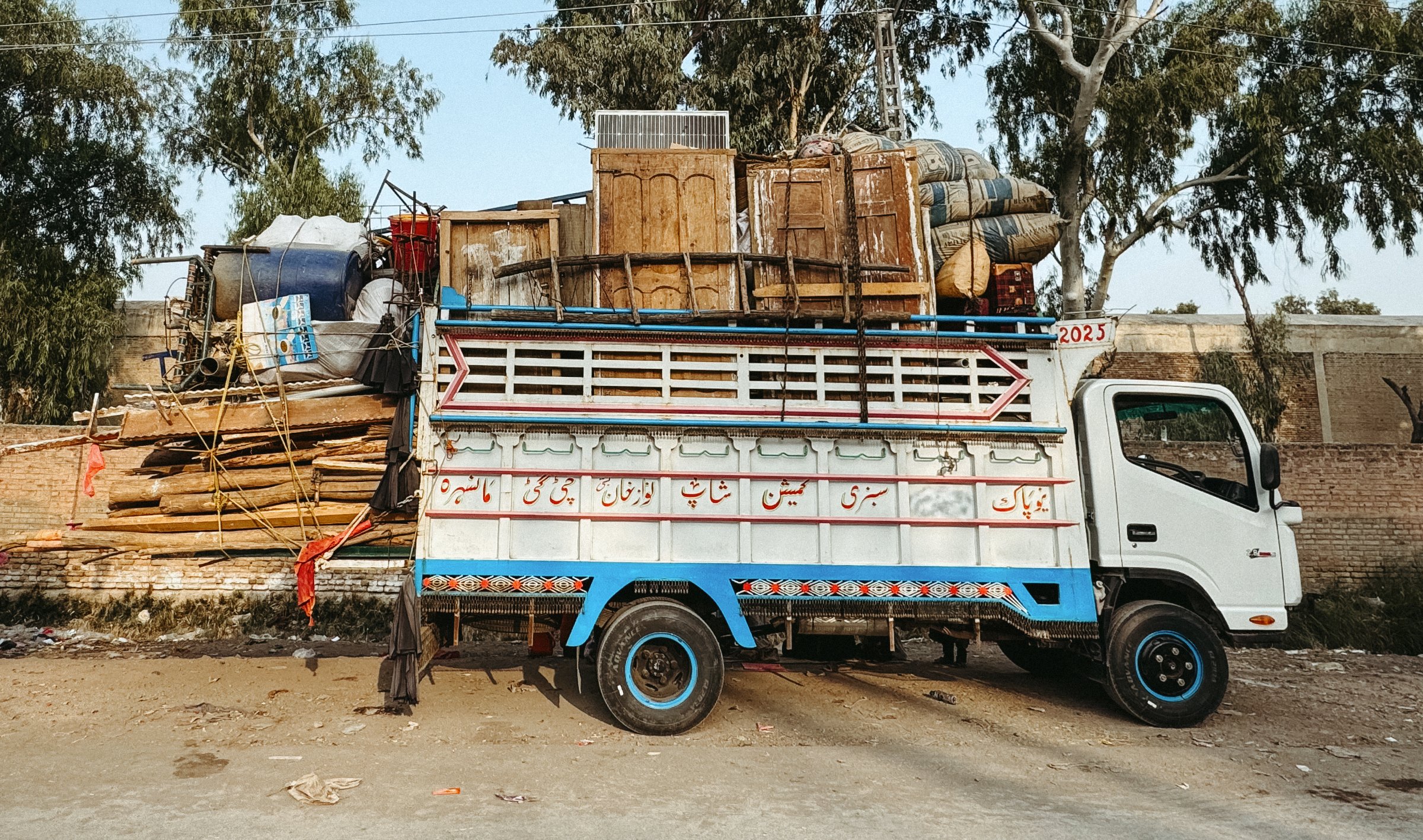 Un camion coloré, surchargé de marchandises diverses, garé sur une route.
