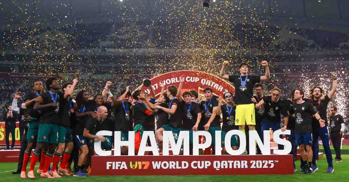 Portugal's players celebrate with the trophy on the podium after the FIFA U17 World Cup final football match between Portugal and Austria at Khalifa International Stadium in Al-Rayyan on November 27, 2025. (Photo by Karim JAAFAR / AFP)