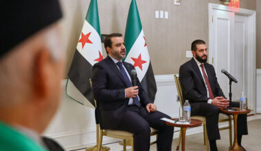 In this photo, released by the Syrian Presidency Press Office, Syrian President Ahmad al-Sharaa, right, listens as Syrian Foreign Minister Asaad al-Shibani, center, speaks during a meeting with representatives of Syrian American organizations in Washington, Saturday, Nov. 8, 2025. (Syrian Presidency Press Office via AP)
