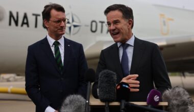 Hendrik Wüst (l, CDU), Ministerpräsident von Nordrhein-Westfalen, Mark Rutte, NATO-Generalsekretär, sprechen vor Mikrofonen, hinter ihnen ist ein Flugzeug der NATO.