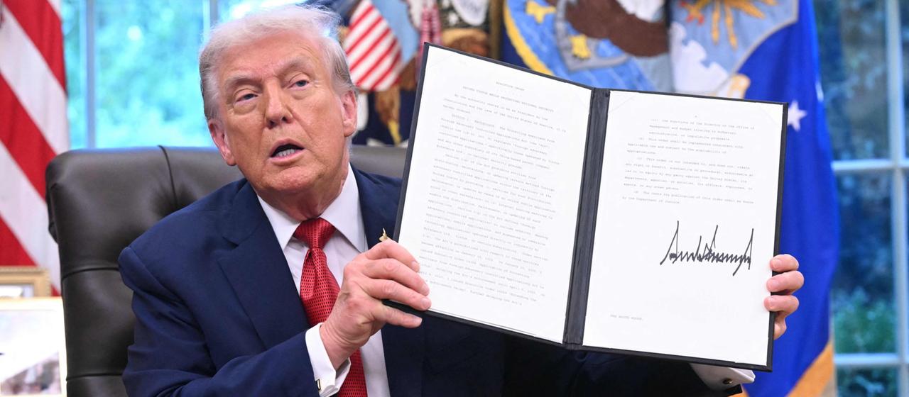 Donald Trump hält im Oval Office eine Präsidentenverfügung.
