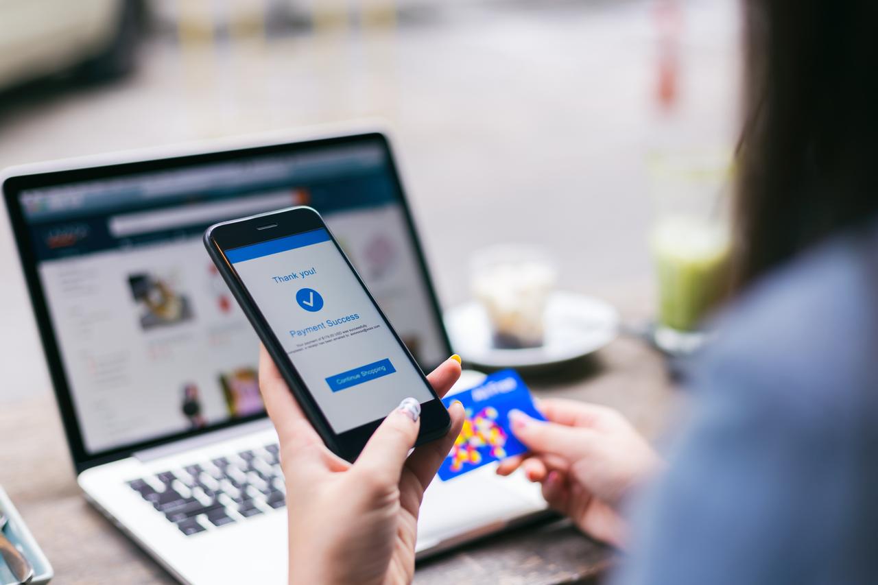 A woman making payment success on mobile smartphone screen and using credit card while shopping on online retail shop with laptop computer, accessed on Nov. 20, 2025. (Adobe Stock Photo)
