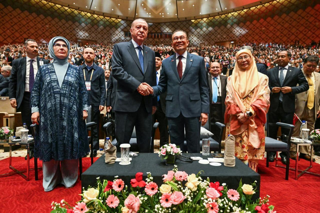 Malaysias PM Anwar Ibrahim (2nd R) shakes hands with President Recep Tayyip Erdogan  (2nd L) next to their wives Türkiyes first lady Emine Erdogan (L) and Malaysias Wan Azizah Wan Ismail (R) during a public lecture at the Putrajaya International Convention Centre in Putrajaya, Malaysia on Feb. 10, 2025. (AFP Photo)