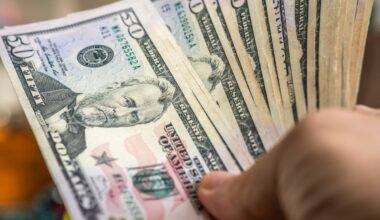 A hand holding a fan of fifty-dollar bills.