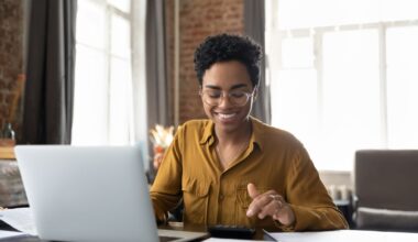 A person smiling while sitting at a computer.