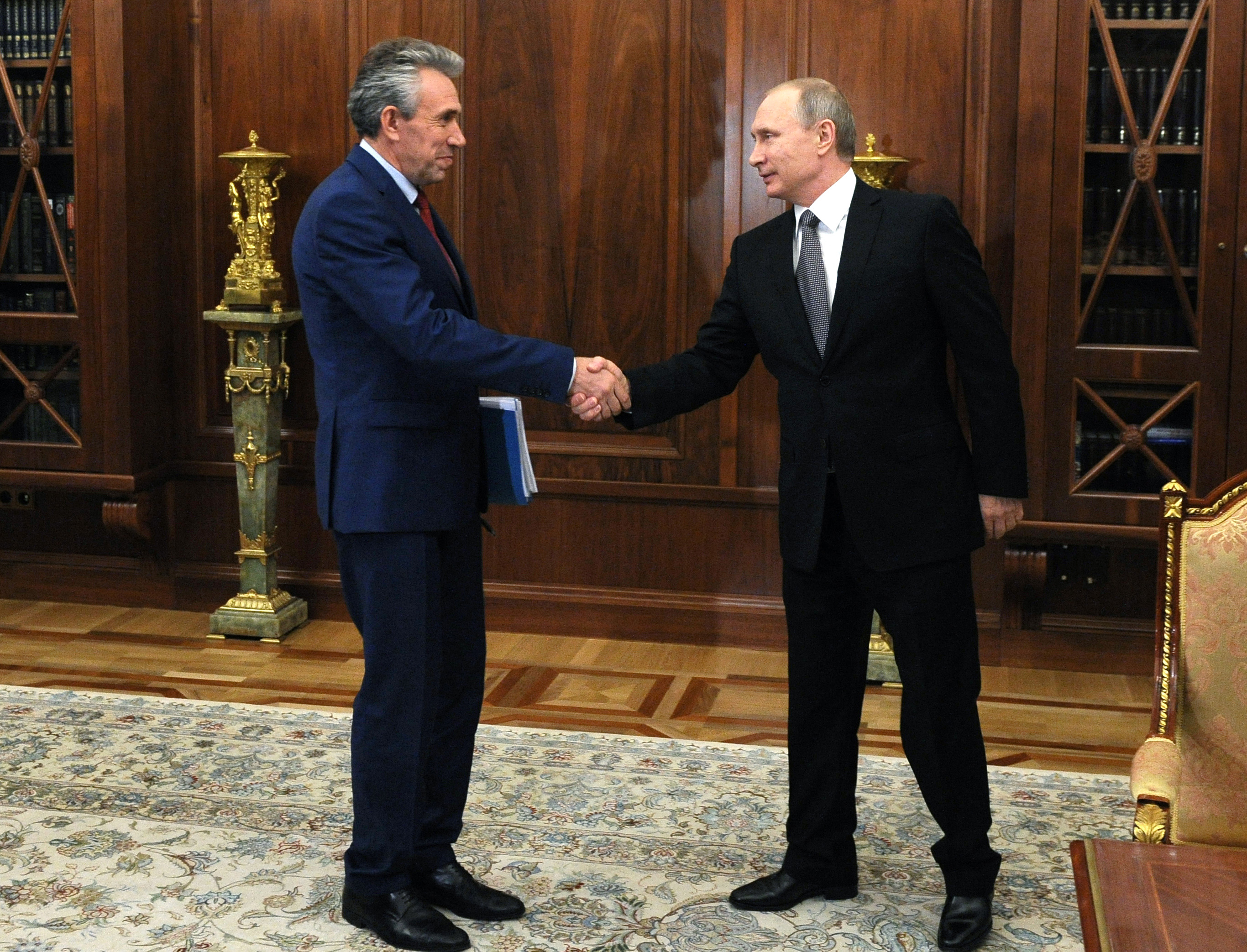 Russian President Vladimir Putin shakes hands with Vnesheconombank Chairman Sergei Gorkov.