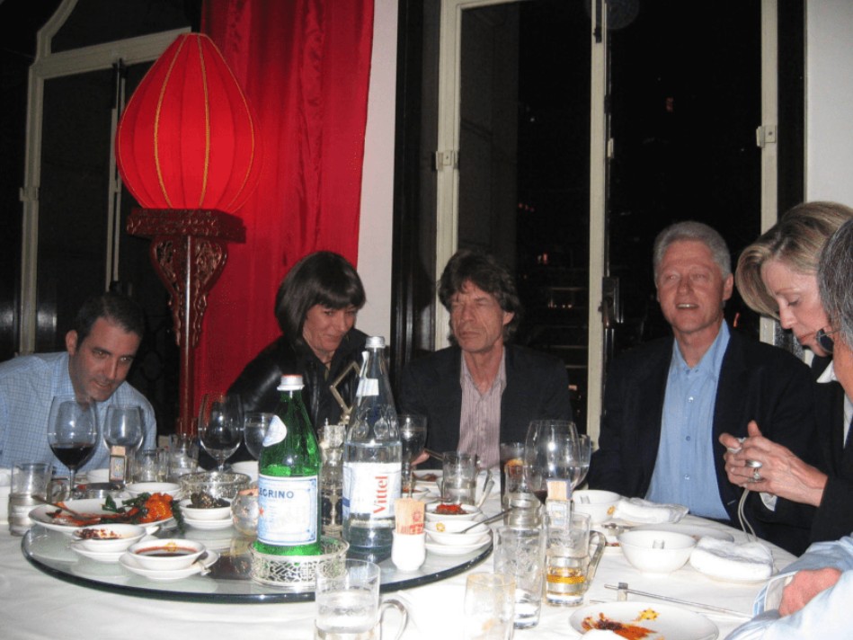 Jagger, Maxwell, and Clinton at a dinner table.