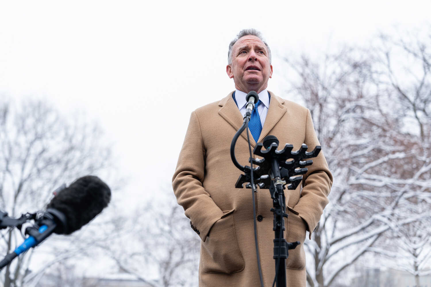 Steve Witkoff wears a coat and stands outside as he speaks into a microphone.