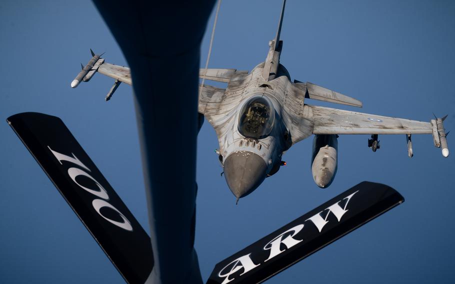 A fighter jet seen past the tail of another plane.