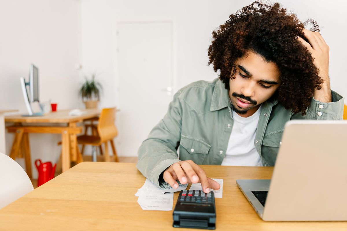 Young adult Latin American man stressed while reviewing bills