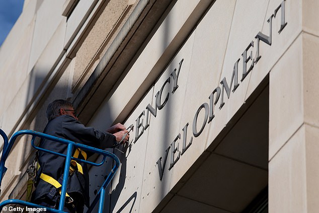 A worker removes the U.S. Agency for International Development sign on their headquarters on February 07, 2025 in Washington, DC