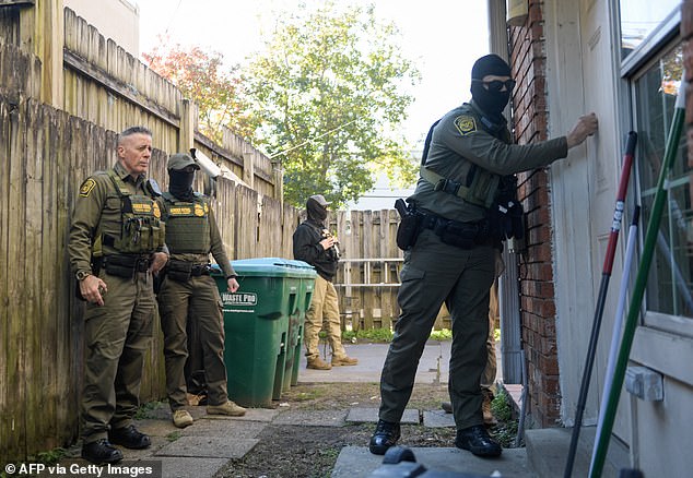 A Customs and Border Patrol agent knocks on a residential door during a walk through the Kenner neighborhood in New Orleans with Border Patrol Commander Gregory Bovino (left) and other law enforcement officers on December 15, 2025