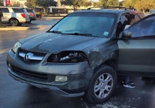 Front view of a damaged gray SUV with the driver's side door open.