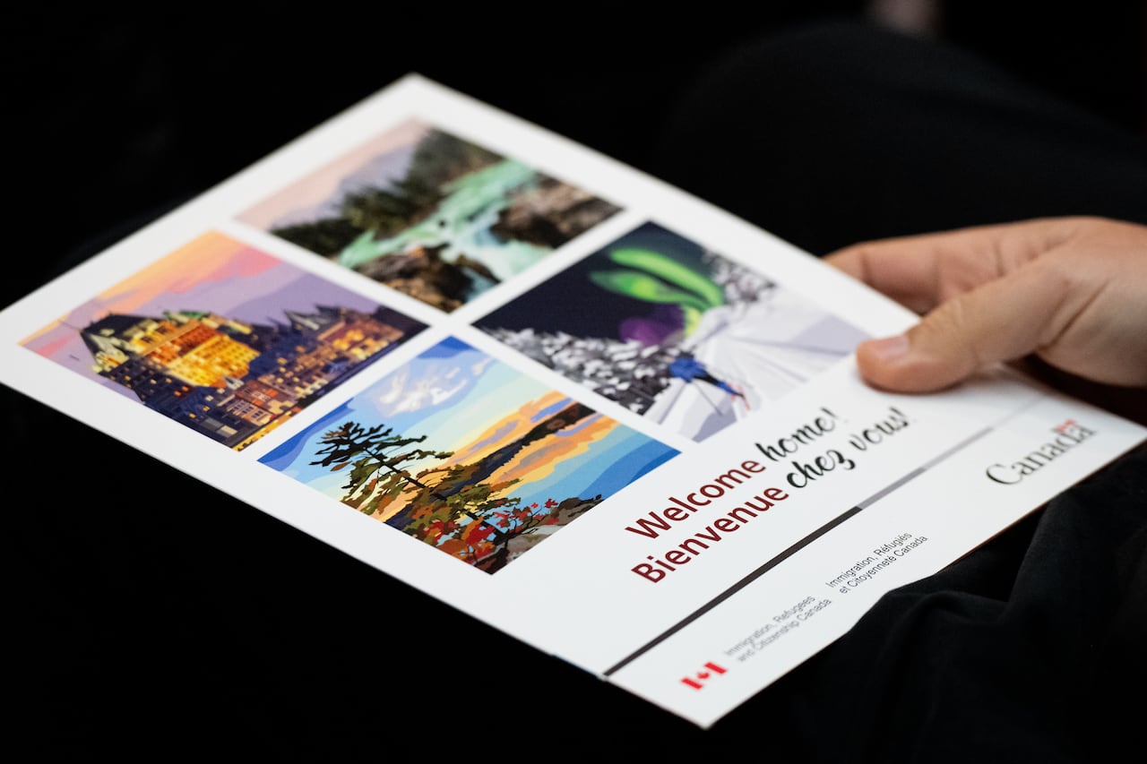 A new Canadian citizen holds a 'Welcome Home' booklet containing a citizenship certificate during a Canadian citizenship ceremony at the Royal Canadian Mounted Police (RCMP) Musical Ride stables in Ottawa, on Wednesday, Nov. 22, 2023.