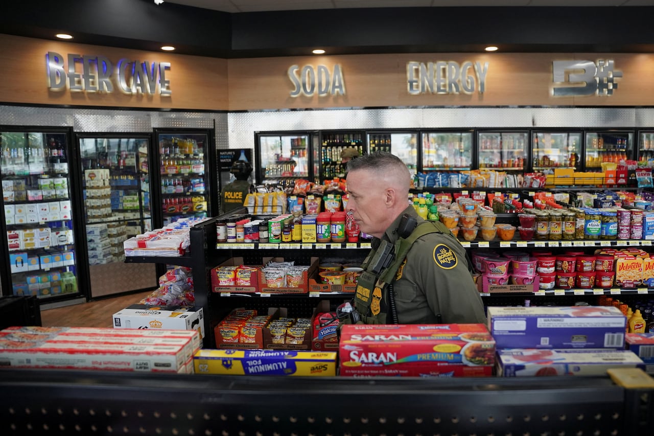 A man walking through an aisle of food and snack products at a gas station