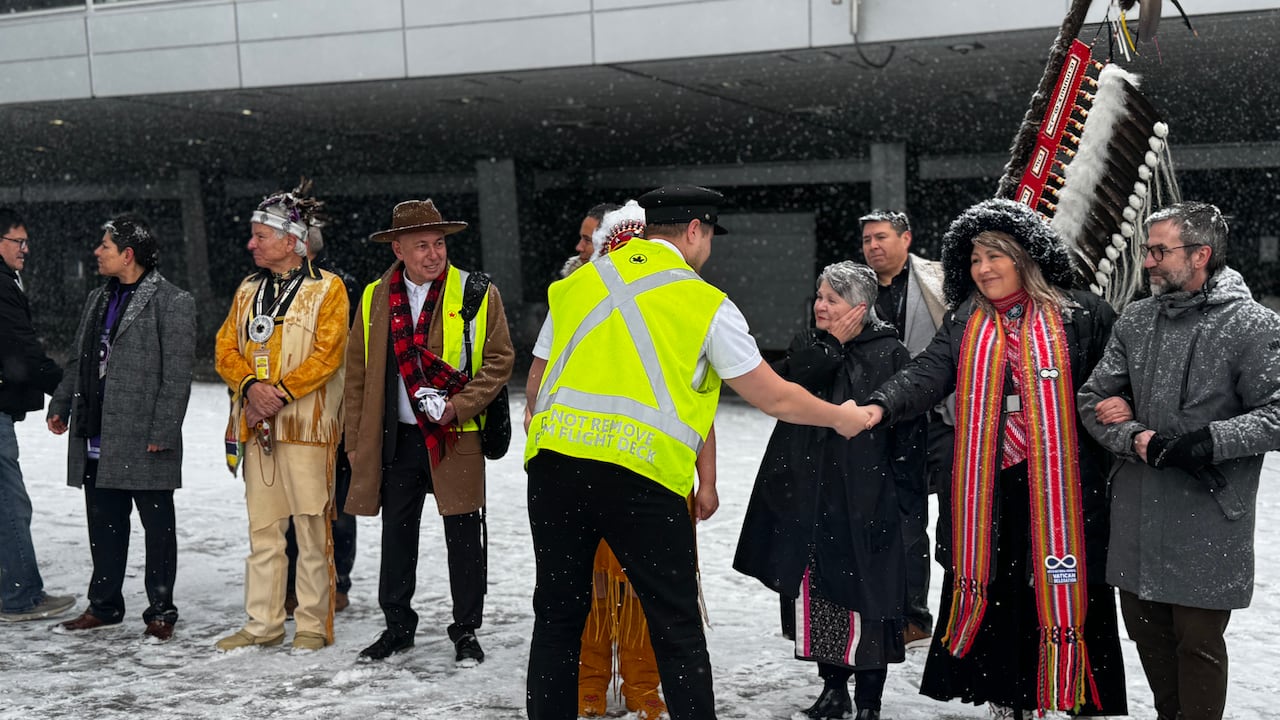 A group of people stand in a line on an airport tarmac.