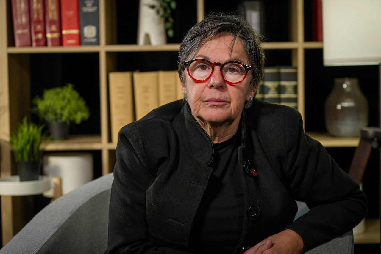 A female Canadian senator wearing a dark outfit and glasses poses for a portrait.