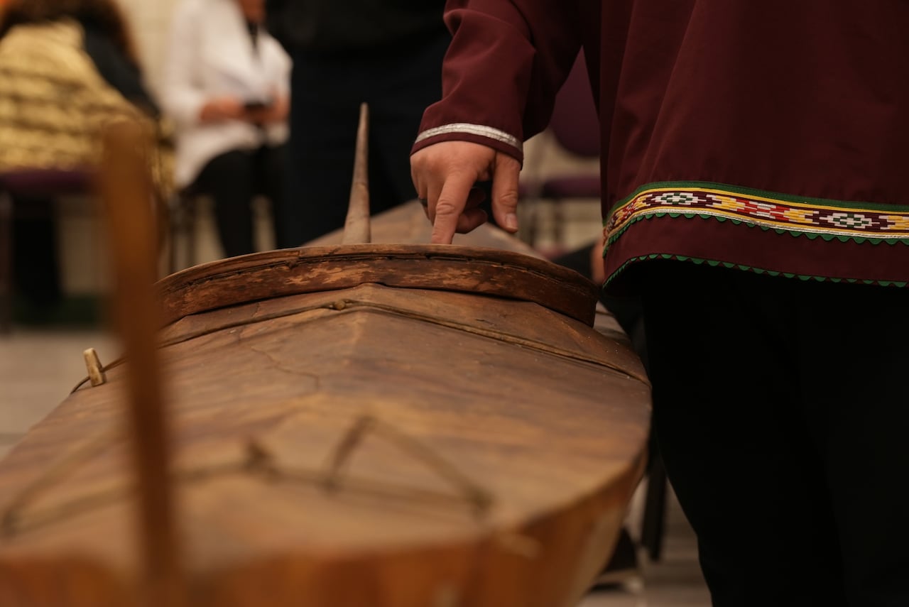 A person's finger is seen touching a brown kayak. 