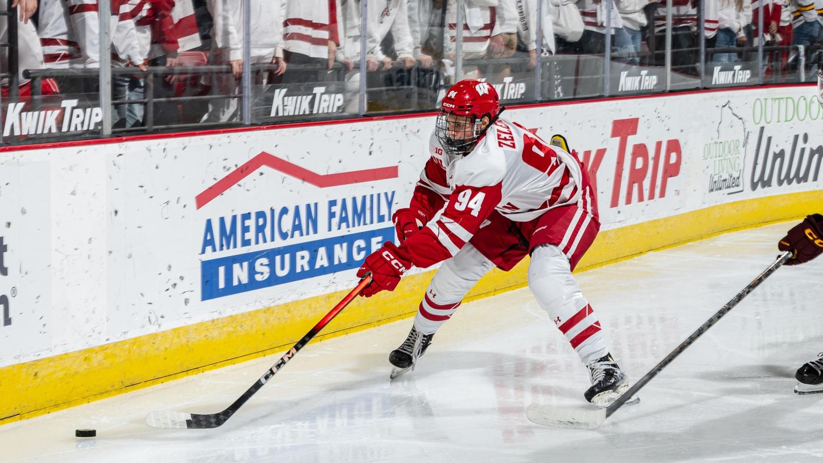 The Badger men's hockey team holding its 2024 Kwik Trip Holiday Face-Off banner and trophy