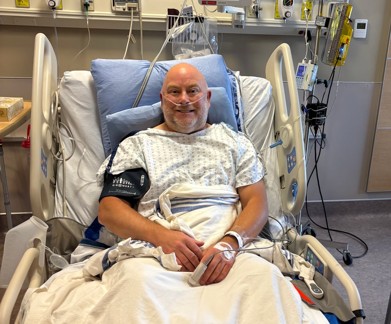 A bald man lies in hospital bed.