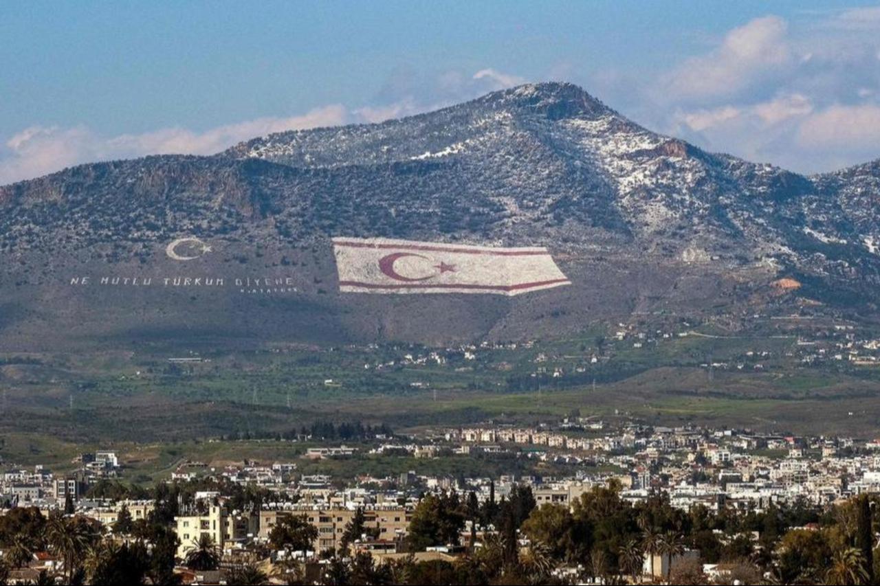 A view of snow covering a portion of Cyprus northern Girne mountain range, above the flag of the Turkish Cyprus (TRNC), Lefkosia on March 13, 2022. (AFP Photo)