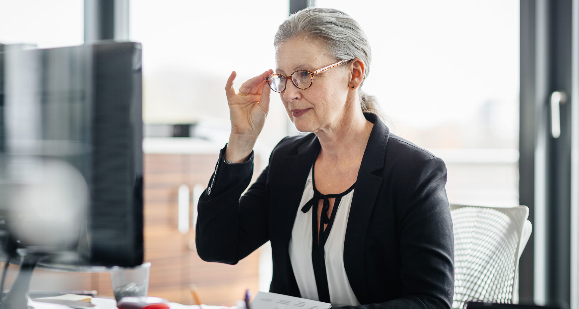 Portrait of a senior businesswoman sitting on her desk in a modern office and.