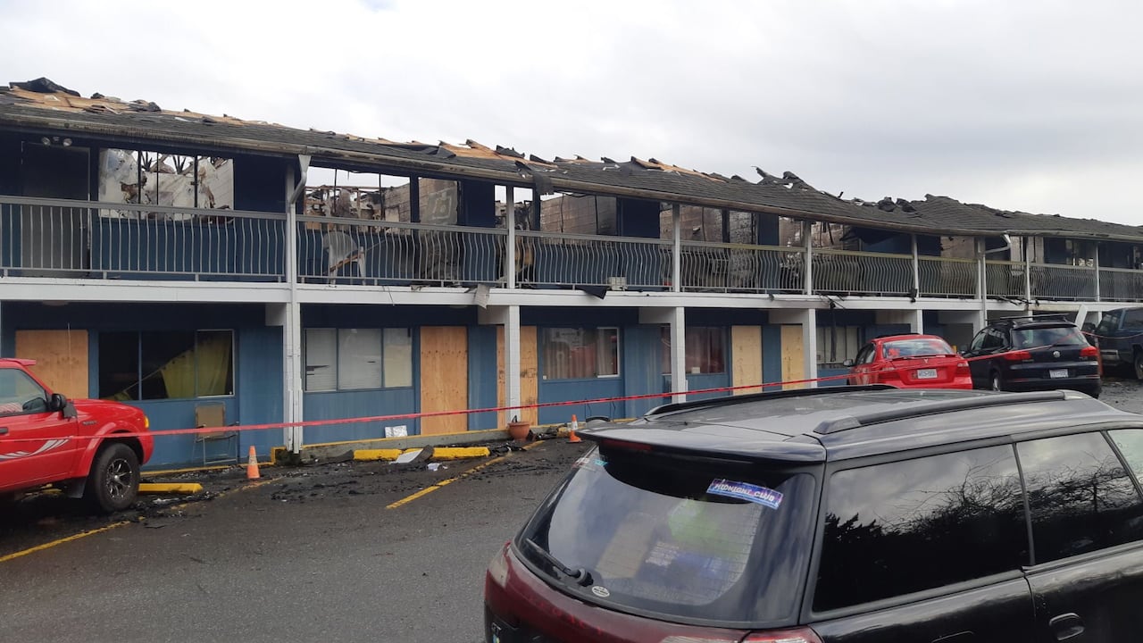 A burnt motel stands with doors and windows boarded up the day after a fire
