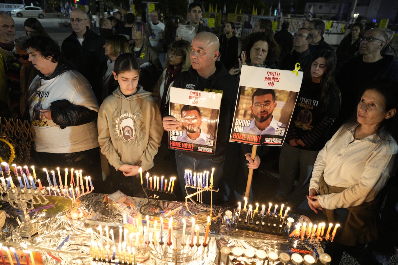 People stand holding candles and photos at a vigil
