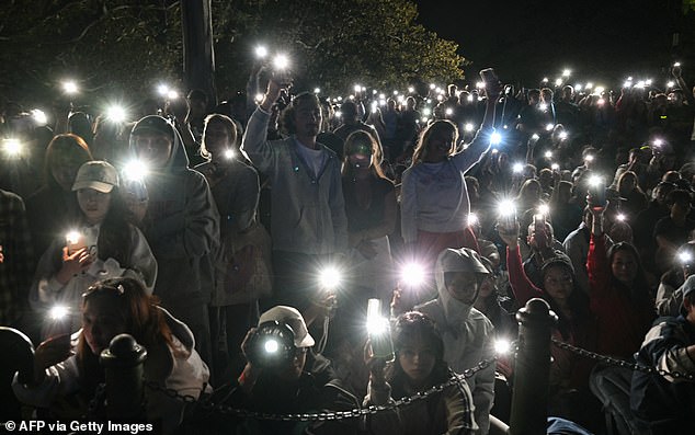 People turn on their mobile phones' flashlights as they observe a minute's silence to reflect on the tragic Bondi Beach shooting attack before New Year's Eve midnight fireworks display in Sydney on December 31, 2025. (Photo by Saeed KHAN / AFP via Getty Images)