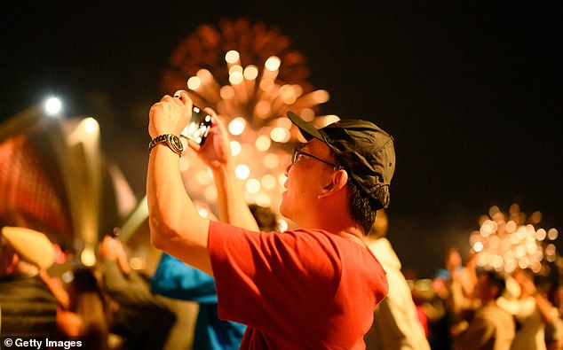 SYDNEY, AUSTRALIA - DECEMBER 31: People enjoy the New Year's Eve firework displays at Opera House on December 31, 2025 in Sydney, Australia. Thousands turned out to celebrate New Year's Eve in Sydney, as the Harbour Bridge lit up with fireworks. (Photo by George Chan/Getty Images)