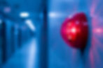 Red alarm light on a blue wall in a corridor, glowing brightly. The background is blurred, creating a tense, urgent mood.