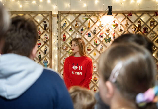 Woman wearing a choliday sweater and children visiting a holiday decoration factory