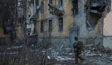 Ukrainian serviceman walks near an apartment building damaged by Russian military strike in the frontline town of Kostiant...