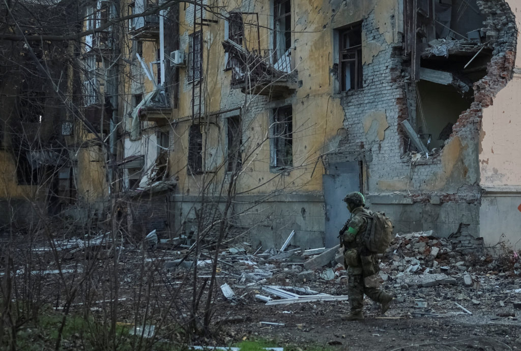 Ukrainian serviceman walks near an apartment building damaged by Russian military strike in the frontline town of Kostiant...