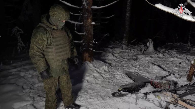 A Russian service member stands next to the remains of a drone, which, according to the Russian Defence Ministry, was downed during the repelling of an alleged Ukrainian attack on the Russian presidential residence in the Novgorod region