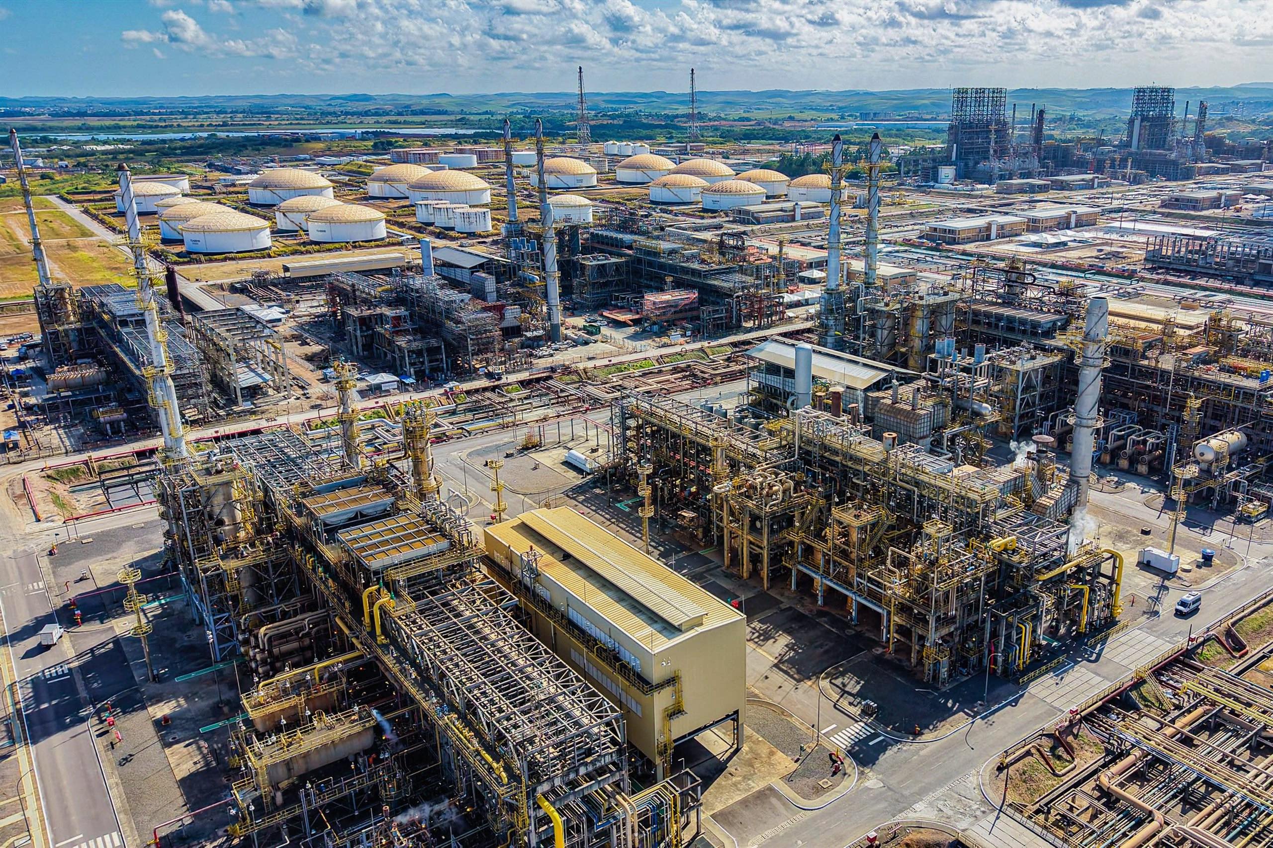 Aerial view of an industrial complex featuring large storage tanks, pipelines, and processing units 