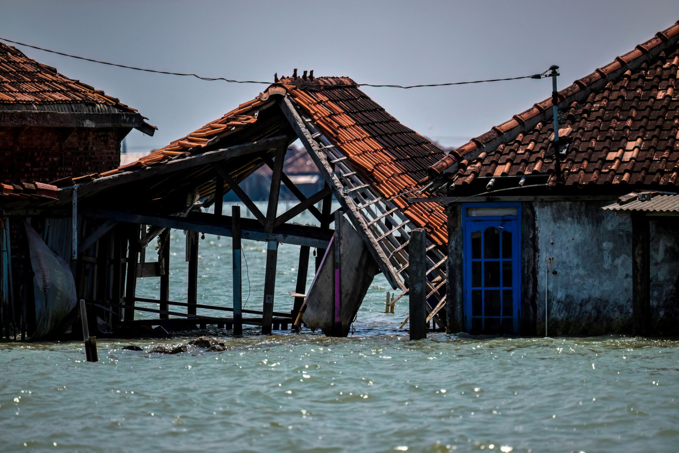 This photo taken on July 30, 2025, shows abandoned and partially submerged houses due to land loss from climate change at Bedono village in Demak, Central Java.