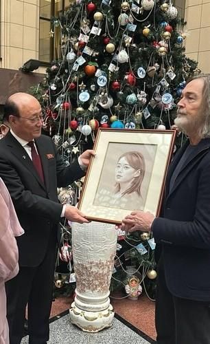 Two men hold up a portrait of Kim Yo-jong, sister of North Korea leader Kim Jong-un, which Maria Zakharova, spokesperson for Russia's foreign ministry, prepared to send to Kim as a gift, in this photo from Zakharova's Telegram account.