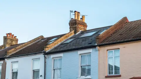 Getty Images Multi-coloured terrace houses with a black roof. They are white, blue and orange.