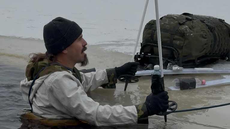 Ian McCollum getting out of a hole in the ice during one of his trips to Finland. 